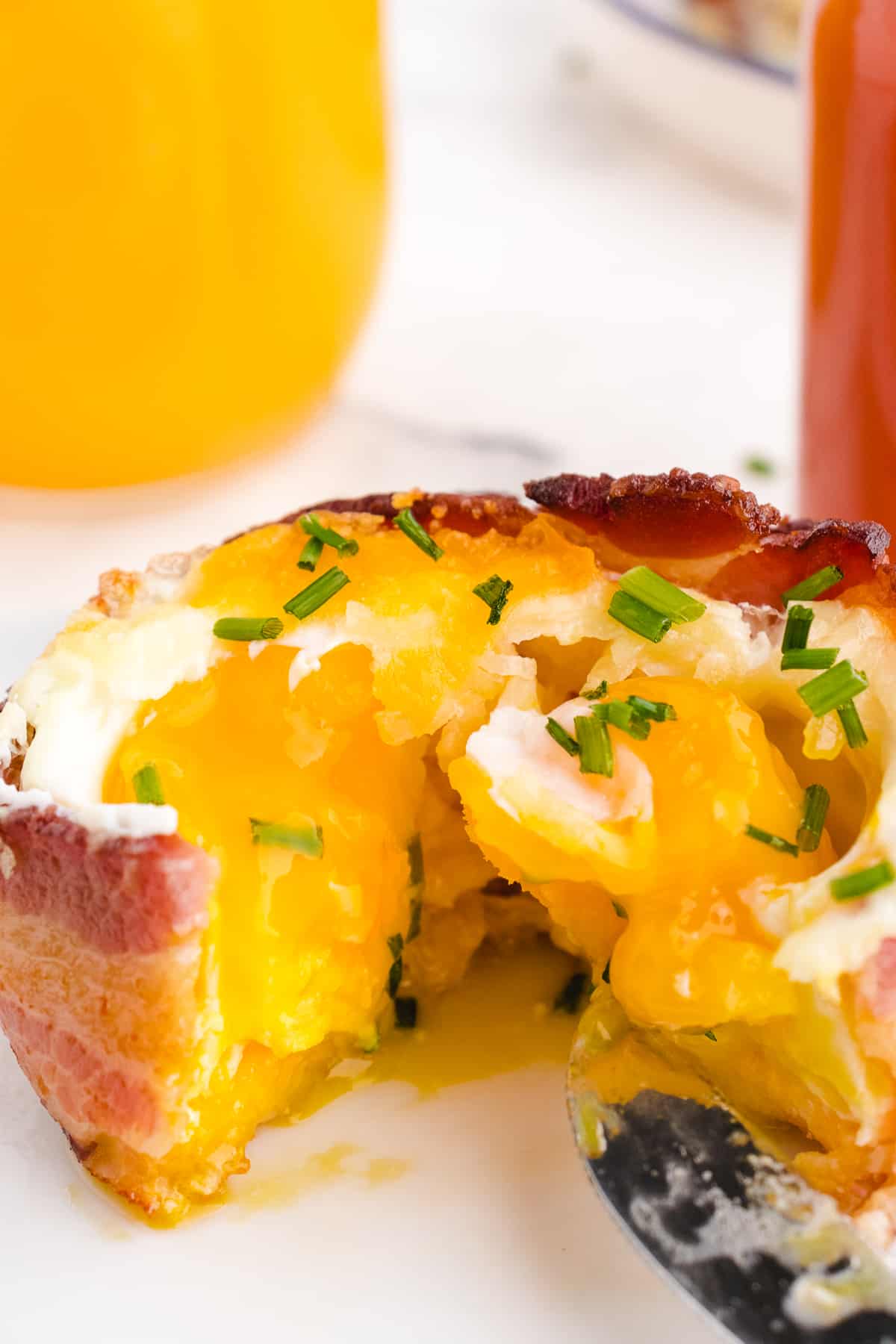 bacon egg and cheese breakfast cups with a cut into the egg so it's running out 