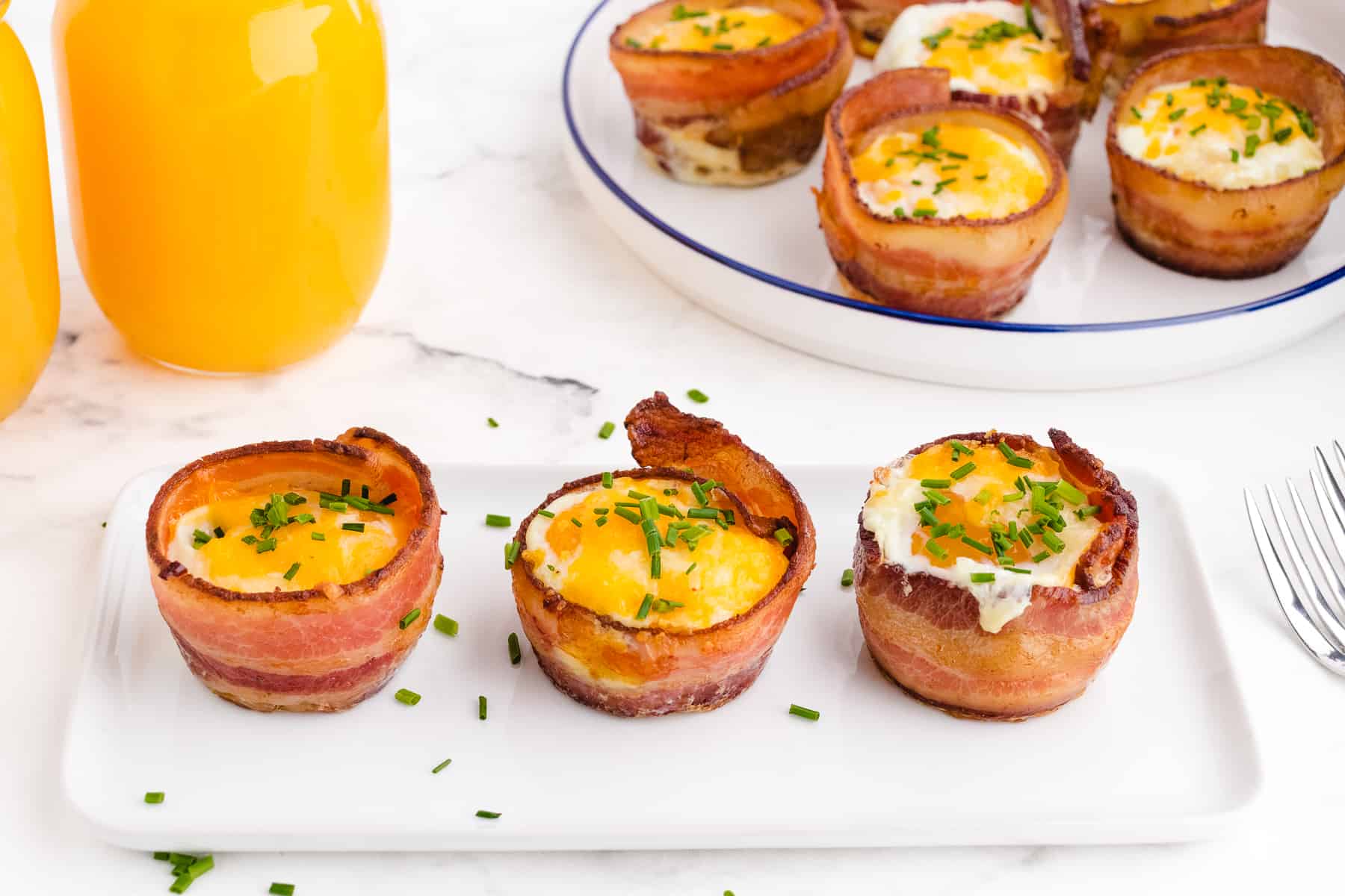 eggs in muffin pan with bacon on a white tray in a single row