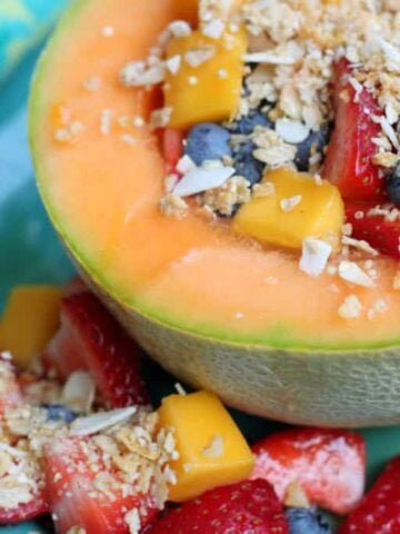 yogurt cantaloupe bowl recipe garnished with granola and fruit on a blue plate