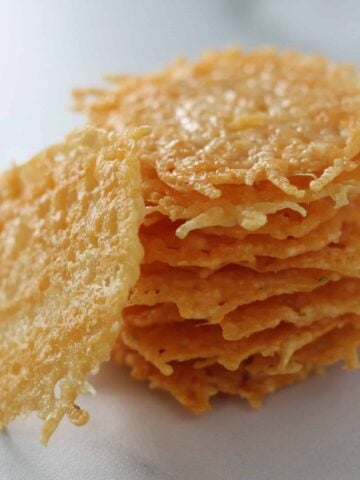parmesan cheese crisps stacked up on a marble cutting board