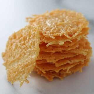 parmesan cheese crisps stacked up on a marble cutting board