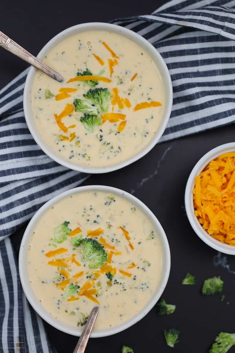 broccoli cheese soup instant pot recipe in white bowls with a cheddar garnish