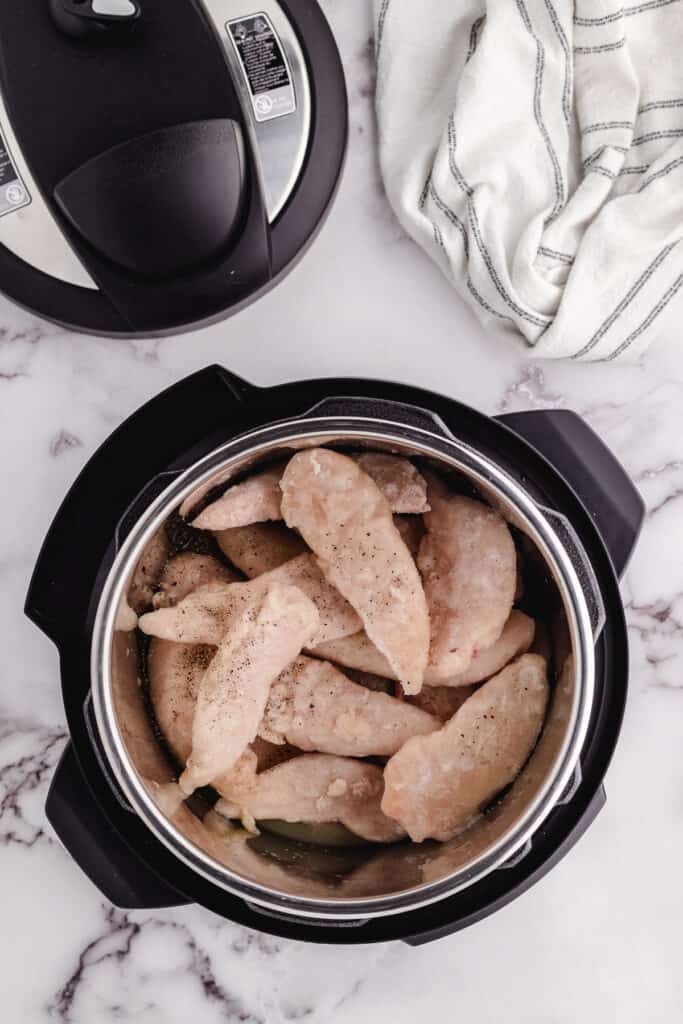 instant pot frozen chicken tenders getting put in the pressure cooker