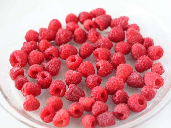 keto custard tart starts with adding raspberries to the bottom of a pie pan