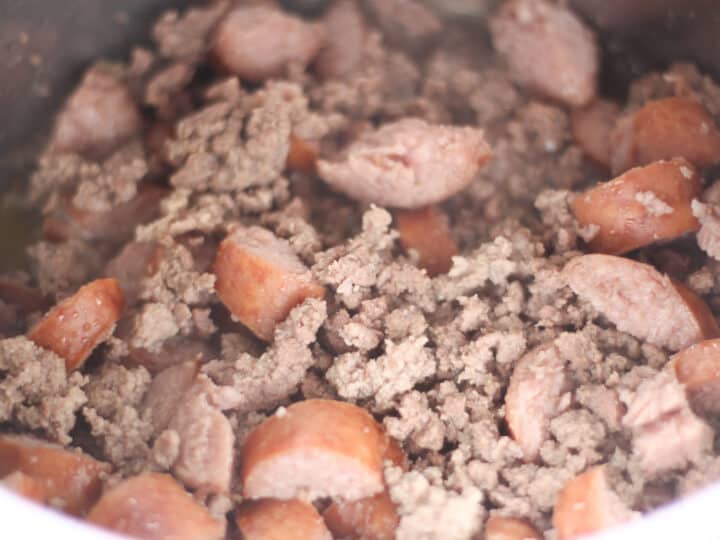 cooking the ground beef and sausage before adding it to the pressure cooker