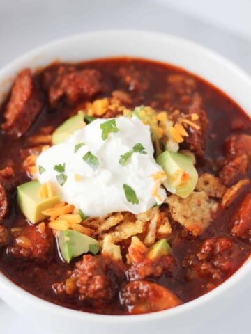 instant pot chili keto in a white bowl garnished with cream cheese and cheese
