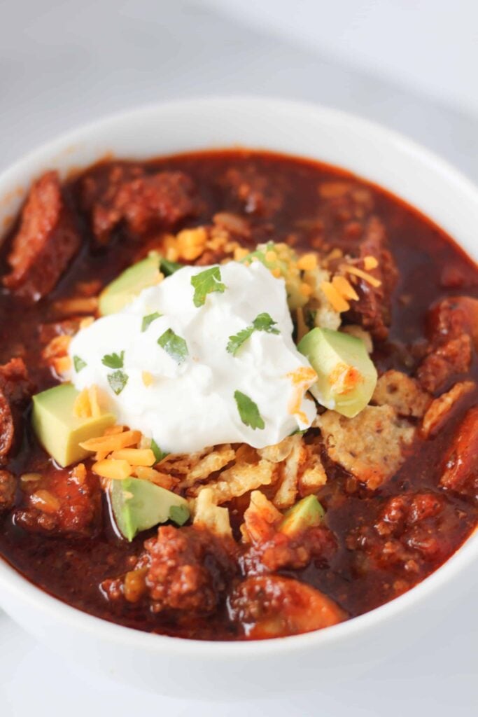 instant pot chili in a bowl with cheese cheese crisps sour cream and cilantro