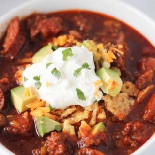 instant pot chili keto in a white bowl garnished with cream cheese and cheese