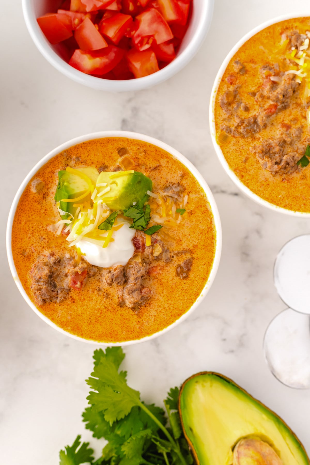 bowls of taco soup topped with garnishes like cilantro and avocado and sour cream