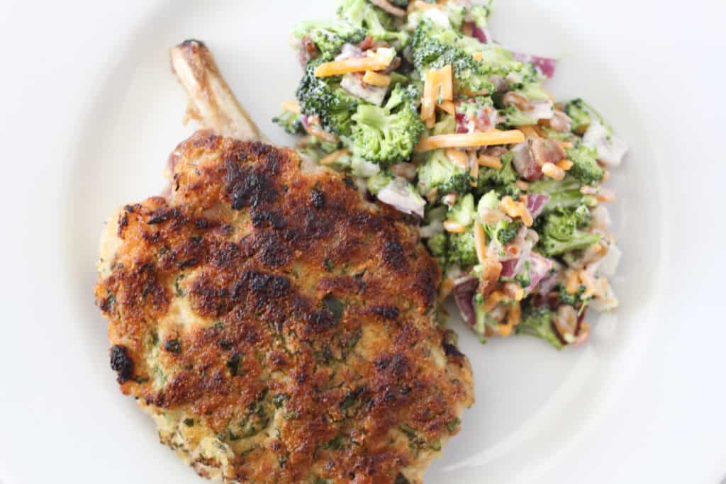 frenched baked pork chops low carb recipe after cooking on a plate with salad after cooking