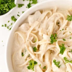 easy alfredo sauce in a white bowl topped with parsley