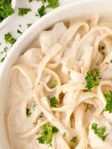 easy alfredo sauce in a white bowl topped with parsley