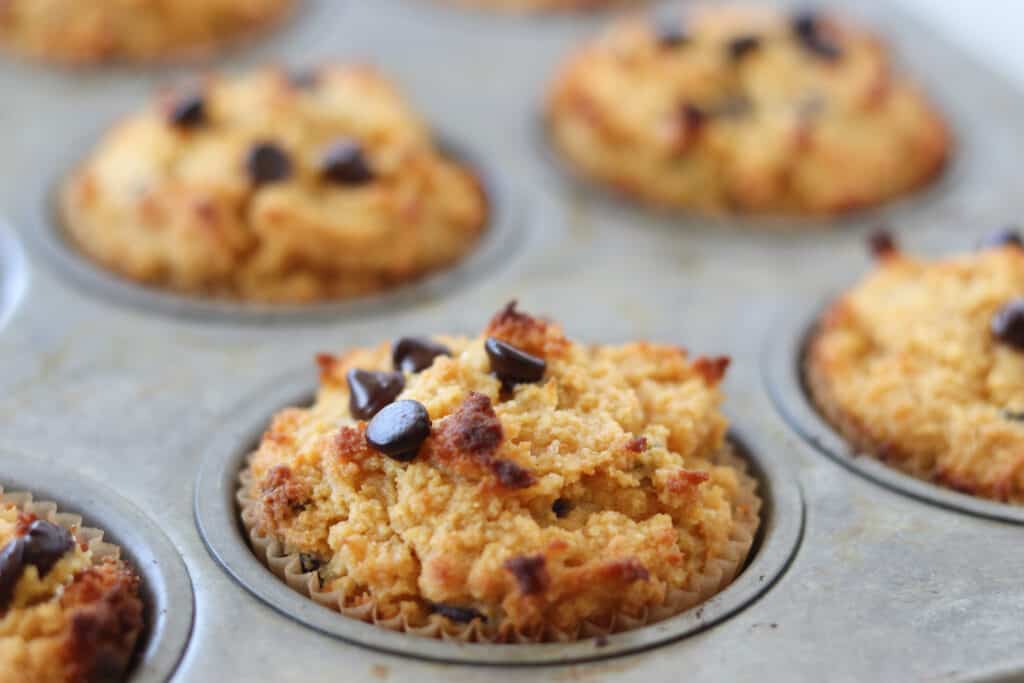keto pumpkin and cream cheese muffins rising in the muffin tin after cooking