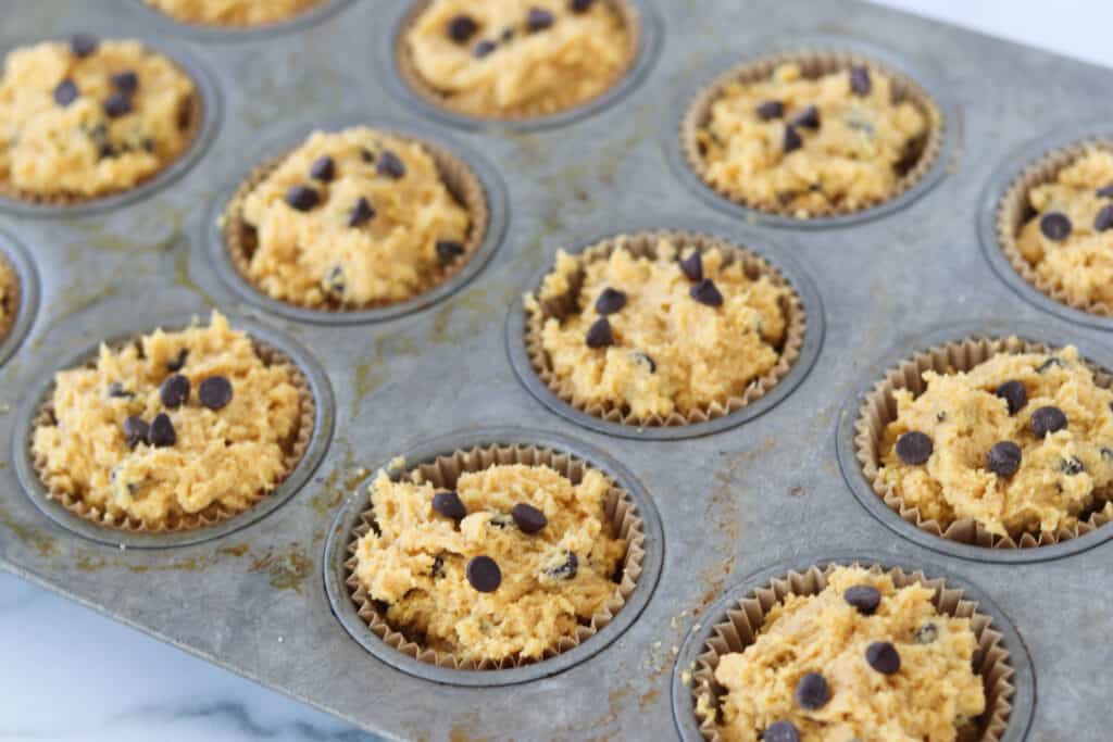 the keto pumpkin muffins batter getting added to the muffin tin