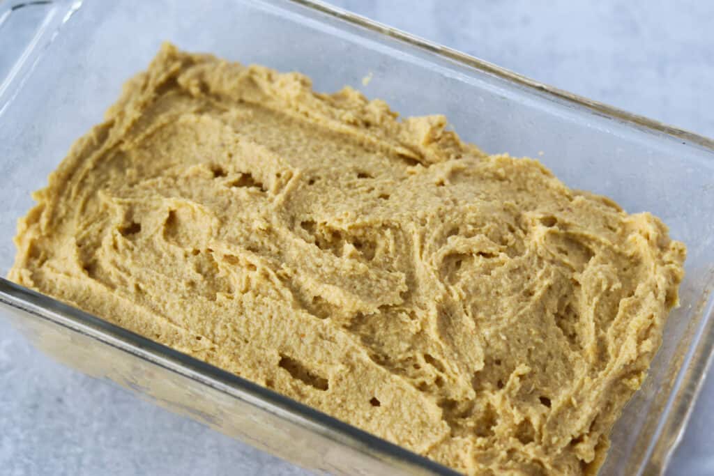 adding the pumpkin bread batter into the pan