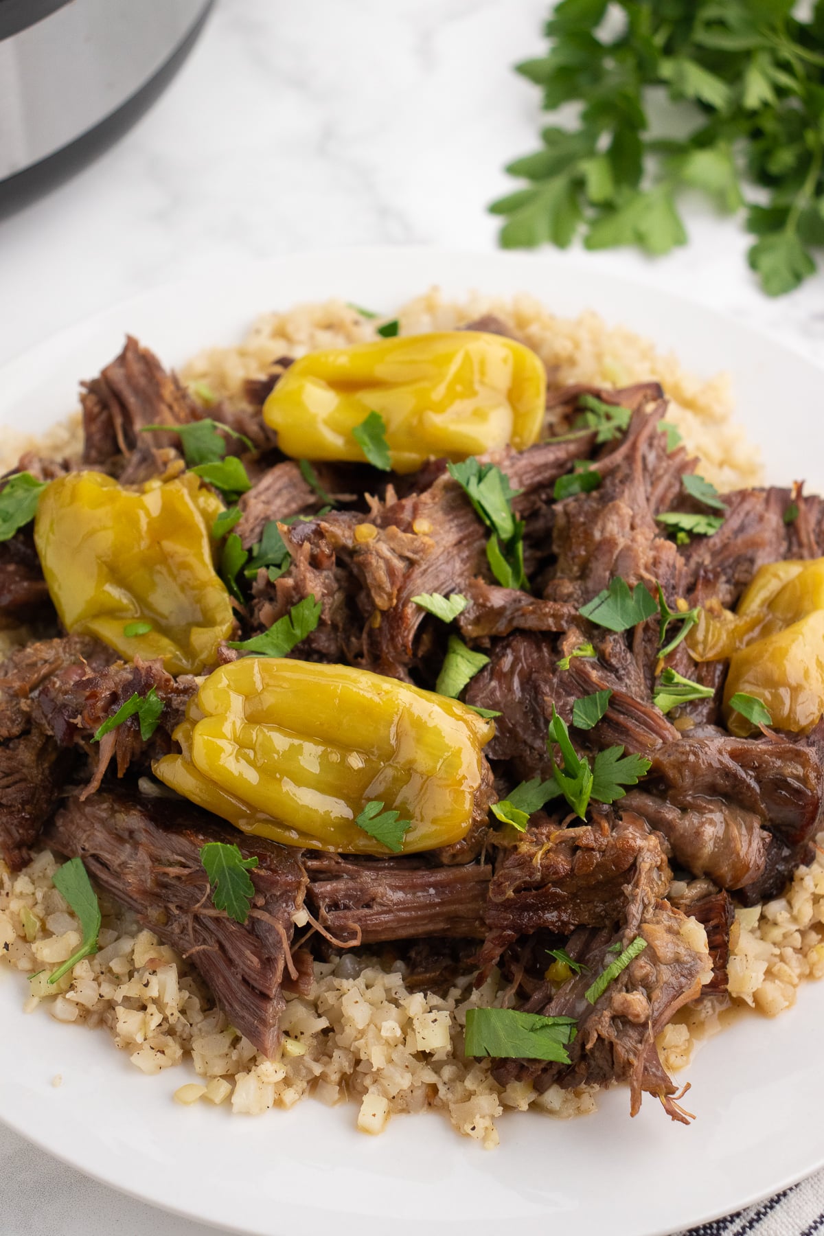 instant pot mississippi pot roast garnished with parsley on a plate with cauliflower rice