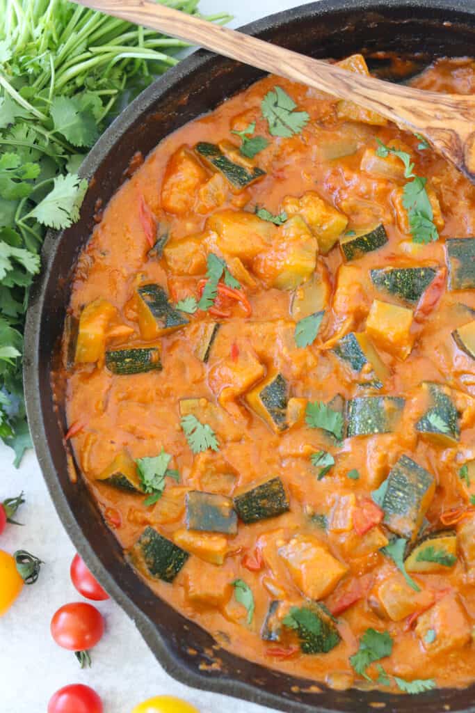 vegan thai red curry in a skillet after cooking with a cilantro garnish on top