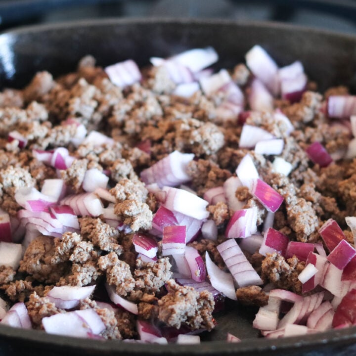 cooking ground beef and onions in a pan for crockpot stuffed pepper soup