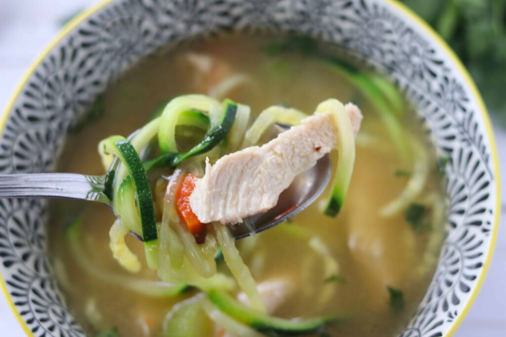 keto chicken noodle soup bite raised up out of a bowl