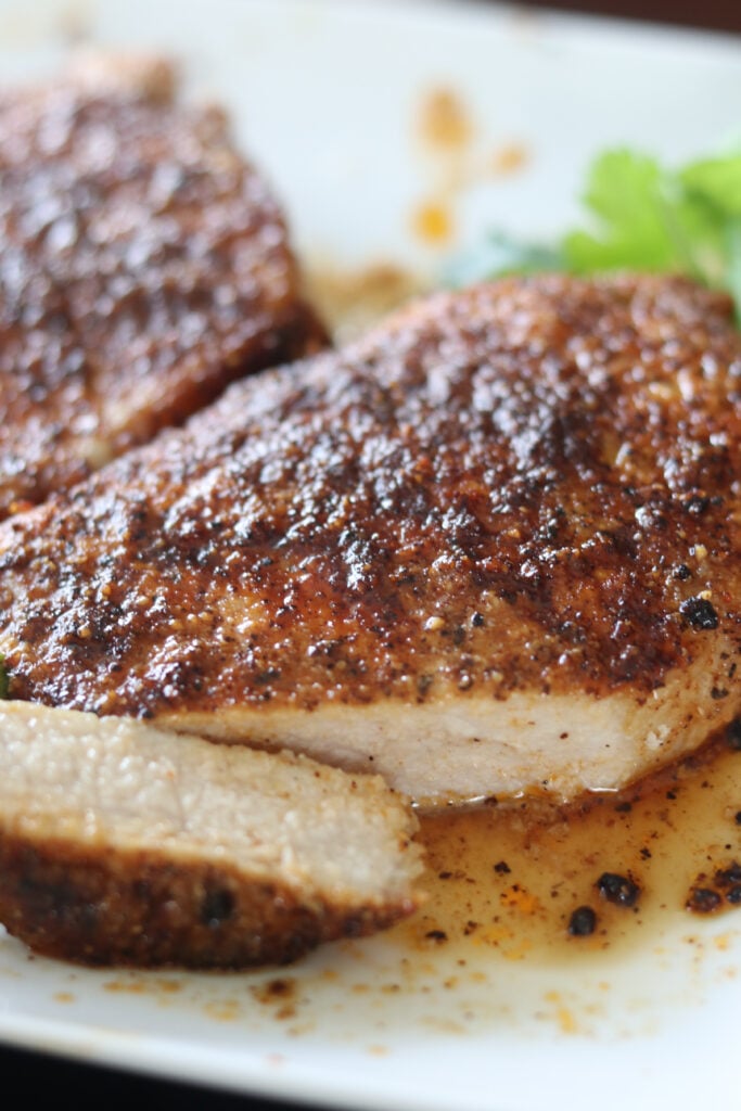 air fryer pork chops recipe with a cut piece on a plate after cooking