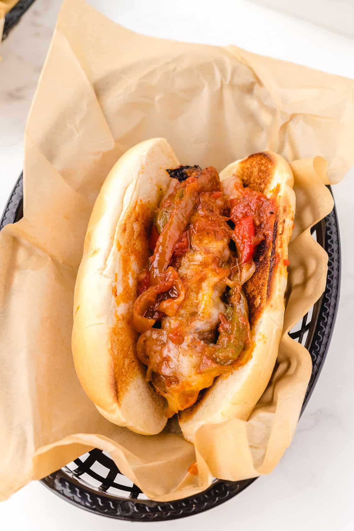 serving sausage and peppers with cheese on a bun