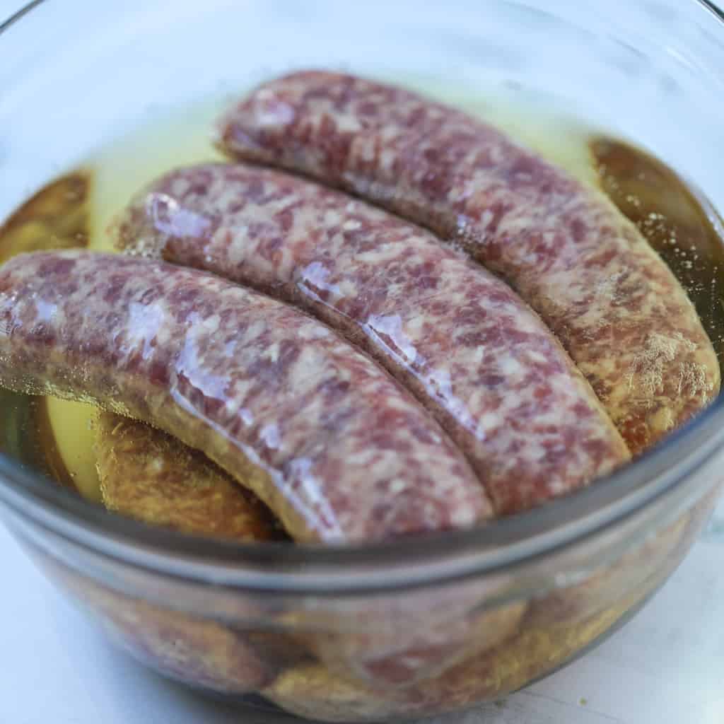 soaking beer baked bratwurst before cooking in a medium size bowl