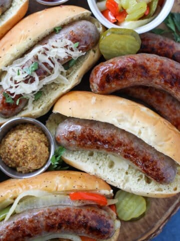 cooking brats in oven served with buns and side dishes