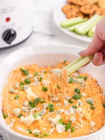 dipping buffalo chicken dip with chicken breast on a celery stick