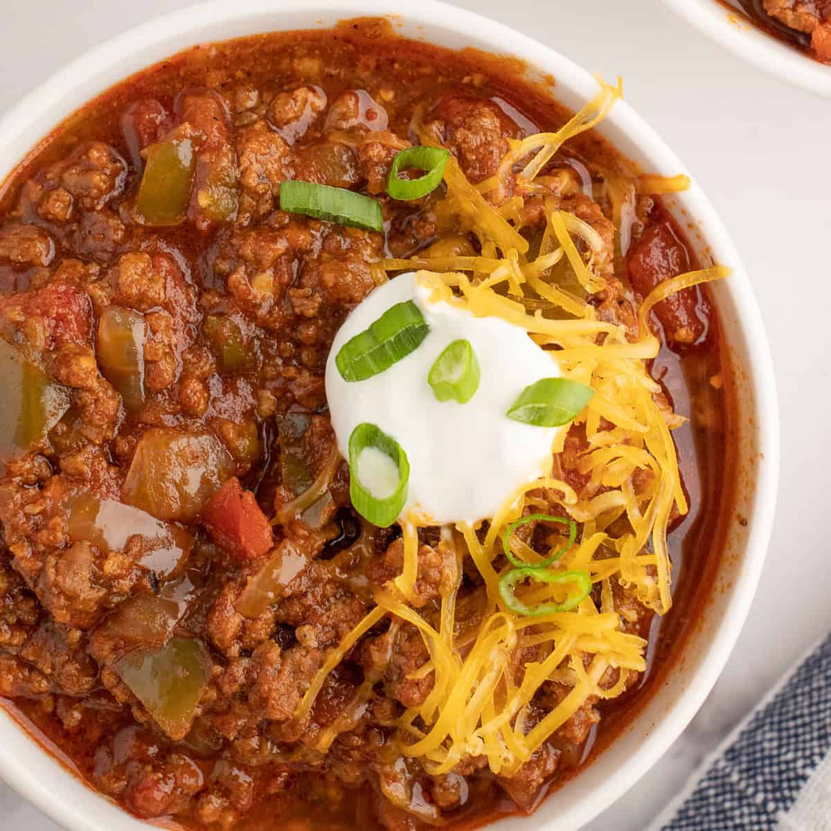 slow cooker chili in a bowl topped with cheese after cooking