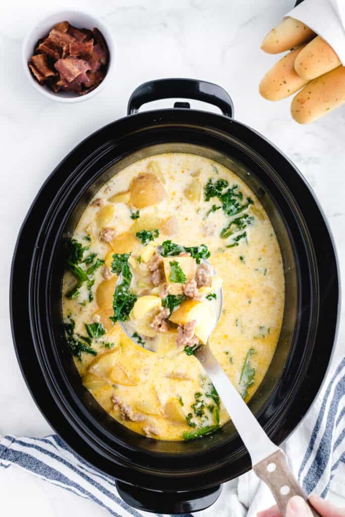 crock pot zuppa toscana in a slow cooker with a bite on a spoon