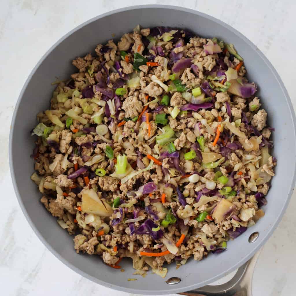 cooking eggroll in a bowl with coleslaw mix in a non-stick skillet