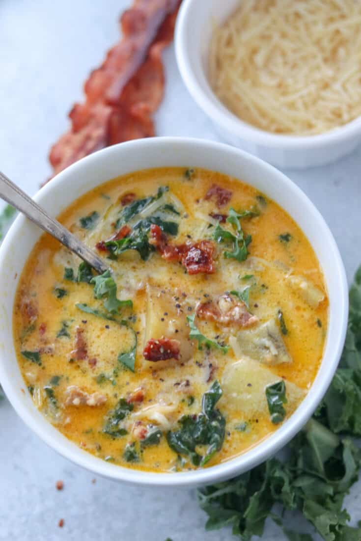 instant pot zuppa toscana in a white bowl with bacon and parmesan on the side