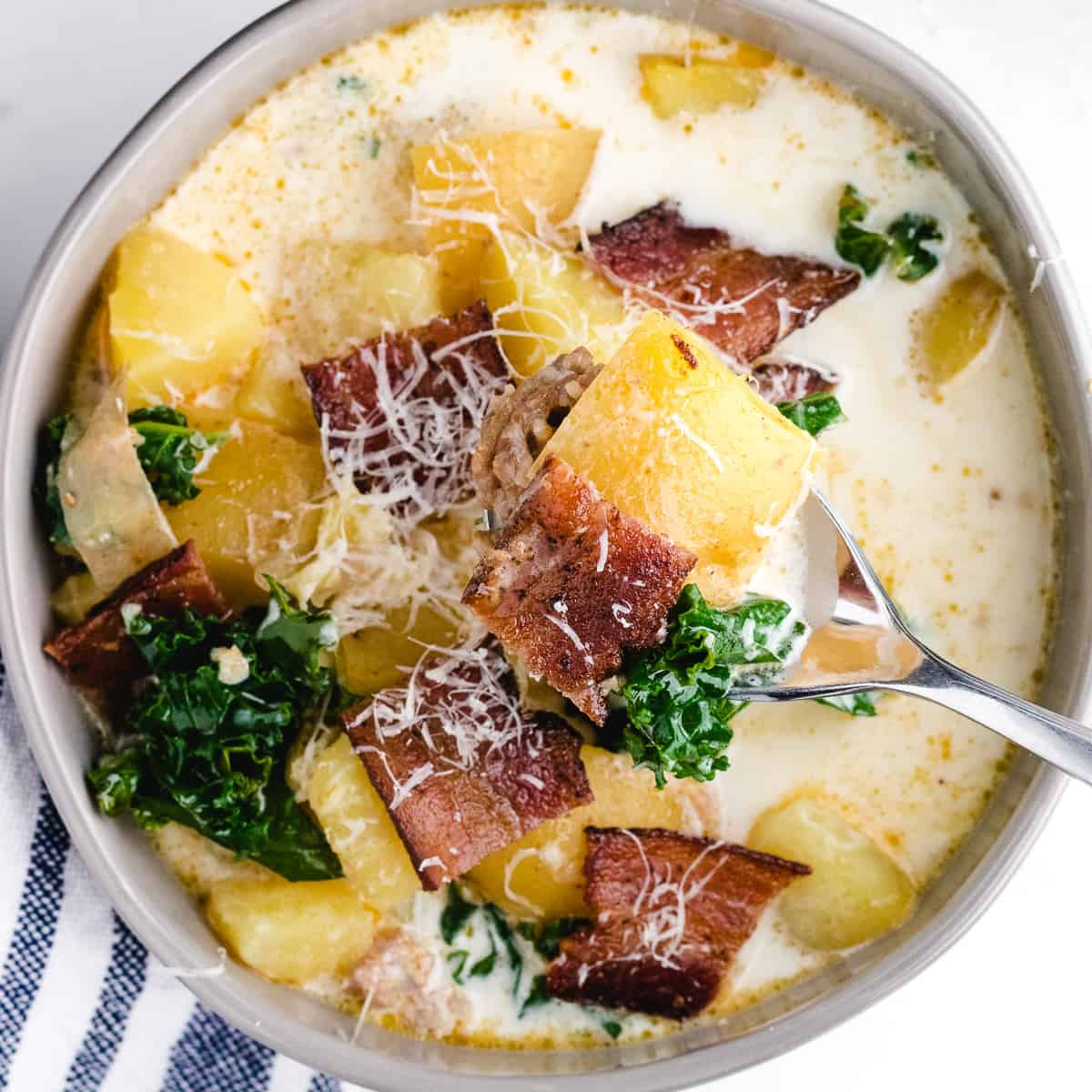 zuppa toscana crockpot in a bowl with bacon garnish