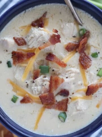 chicken bacon ranch soup in a blue bowl with garnishes