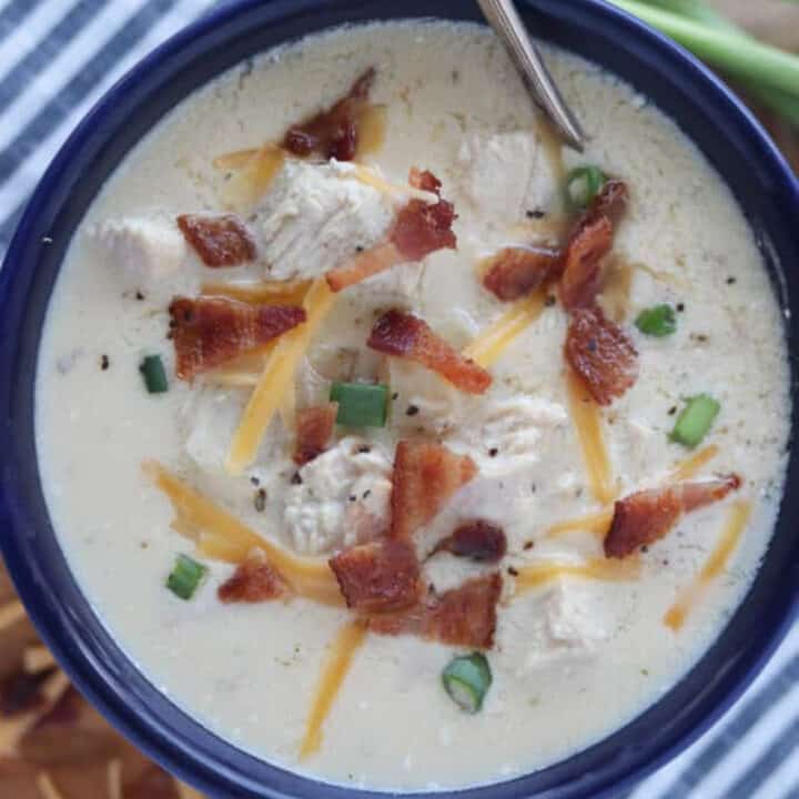 chicken bacon ranch soup in a blue bowl with garnishes