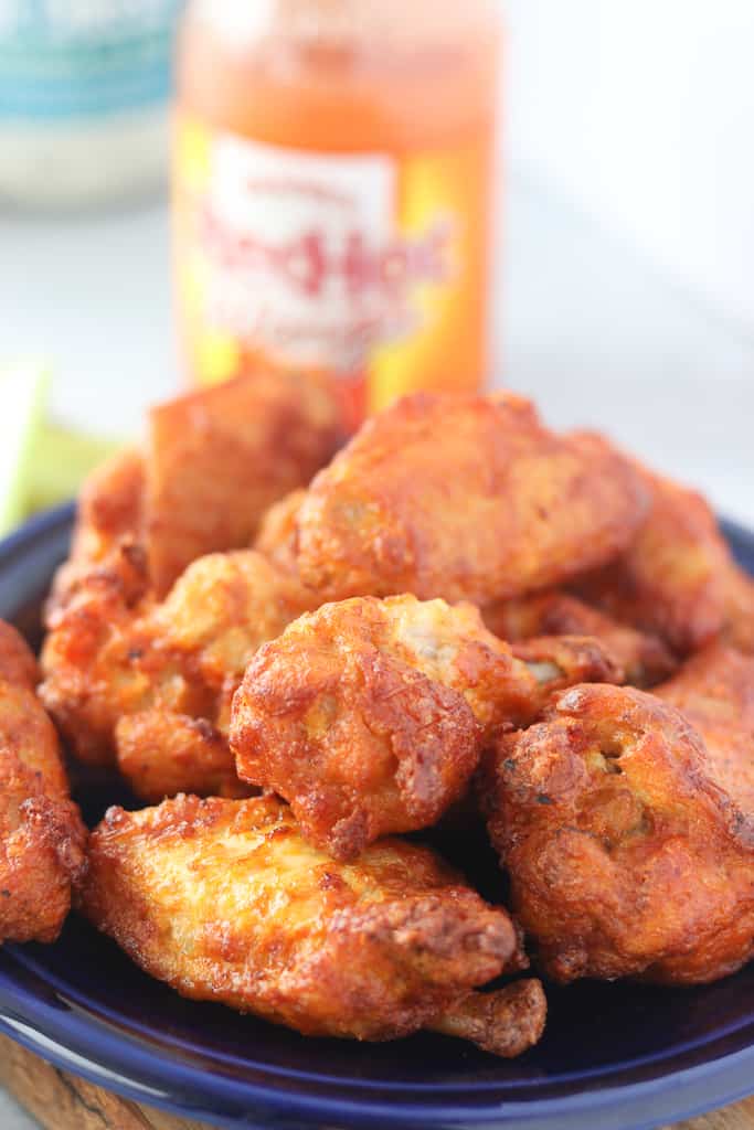 frozen chicken wings in air fryer next to a bottle of franks red hot