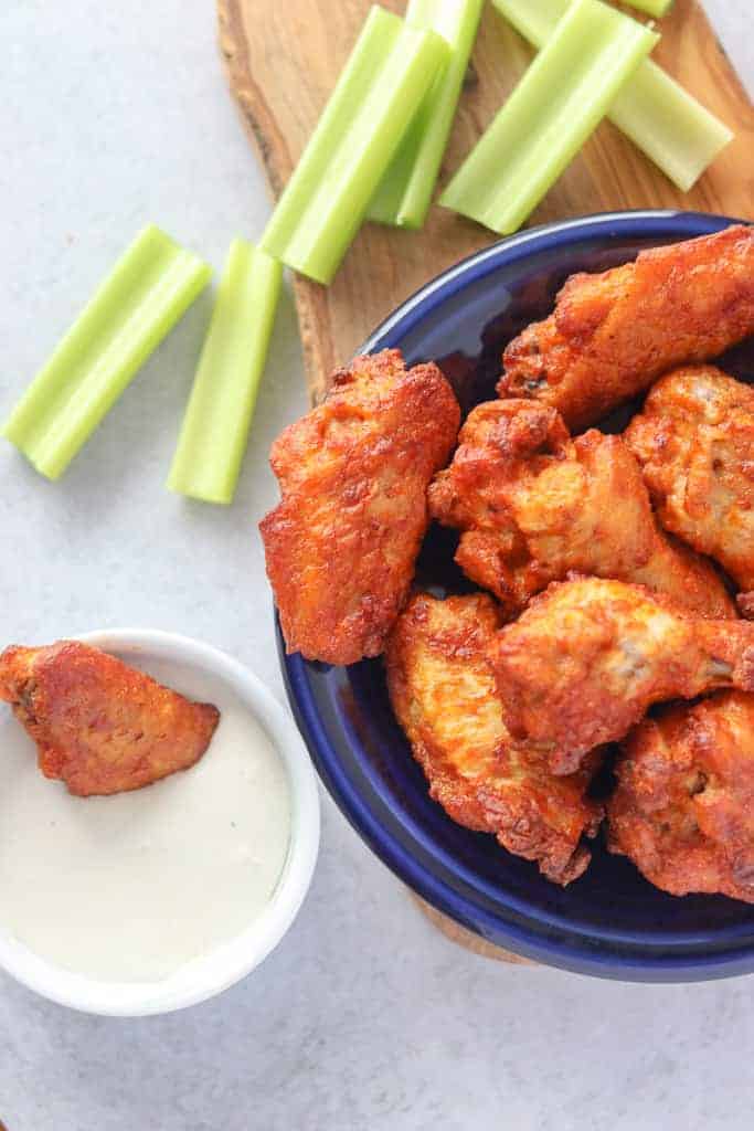 frozen wings in air fryer after cooking with a wing dipped in blue cheese