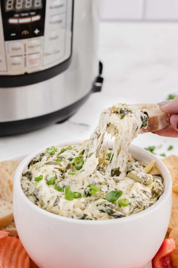 instant pot spinach artichoke dip getting scooped with bread