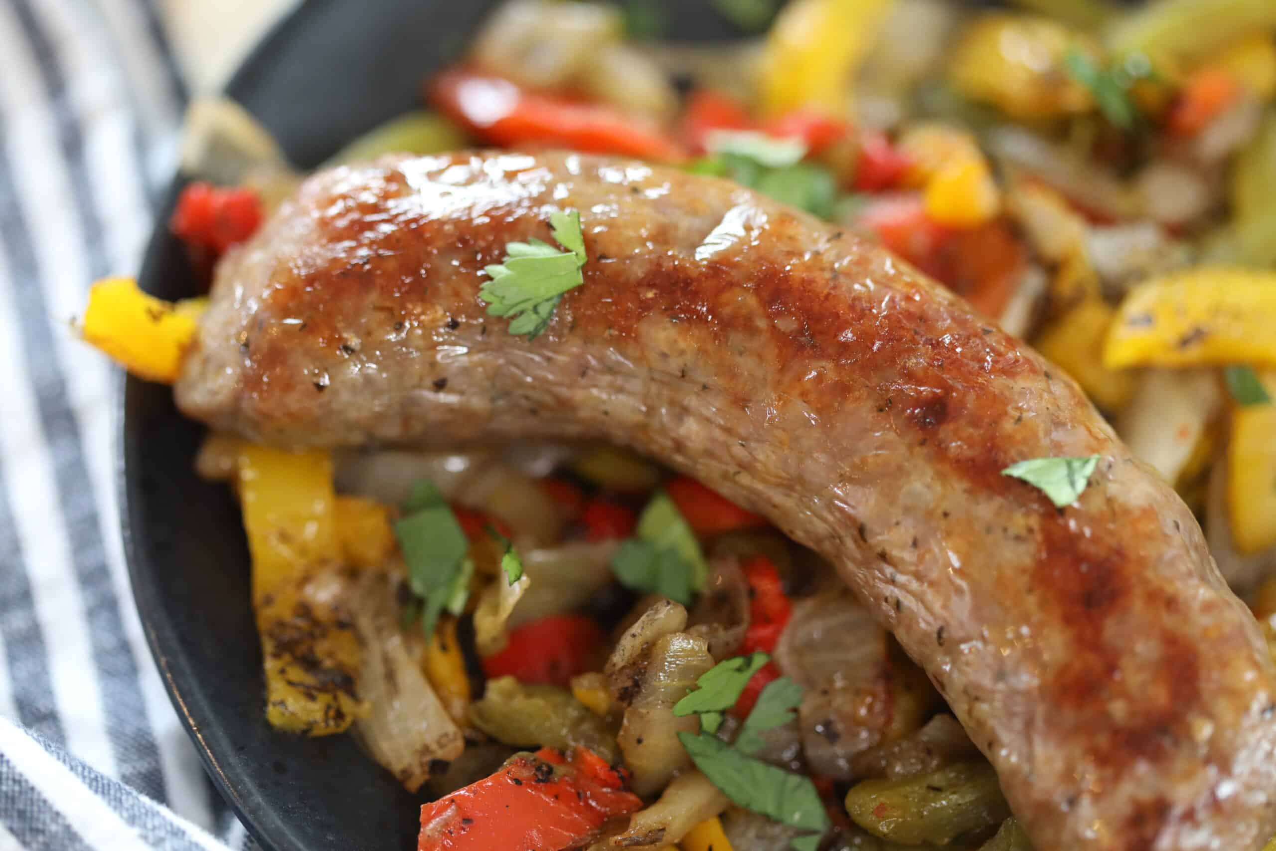air fryer sausage peppers and onions on a black plate after cooking