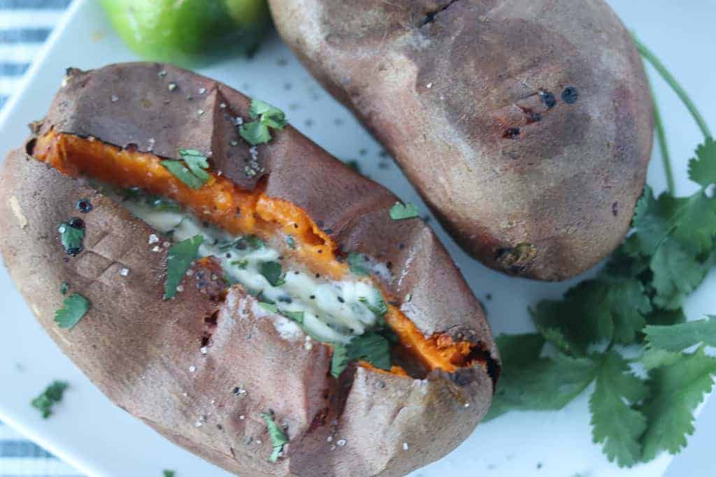 a roasted sweet potato air fryer variety on a plate cut open and fluffed with butter