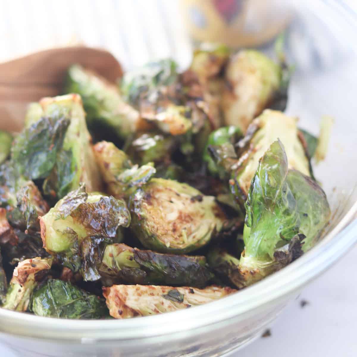 brussel sprouts in air fryer image after cooking in a clear glass bowl next to balsamic glaze