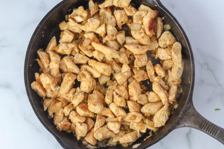 cooking chicken in a pan for keto enchilada bake