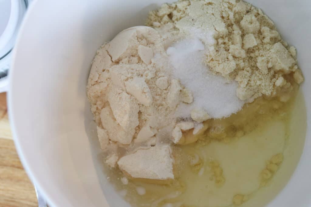 keto pie crust with coconut flour and other ingredients getting added to a bowl