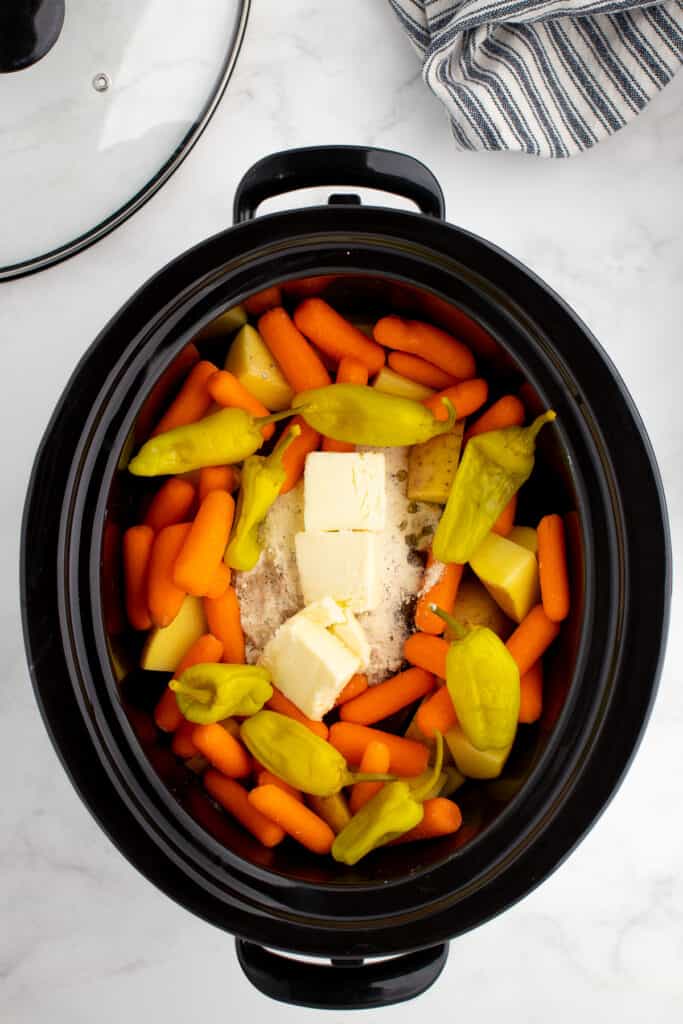 adding mississippi roast with potatoes and carrots to the slow cooker