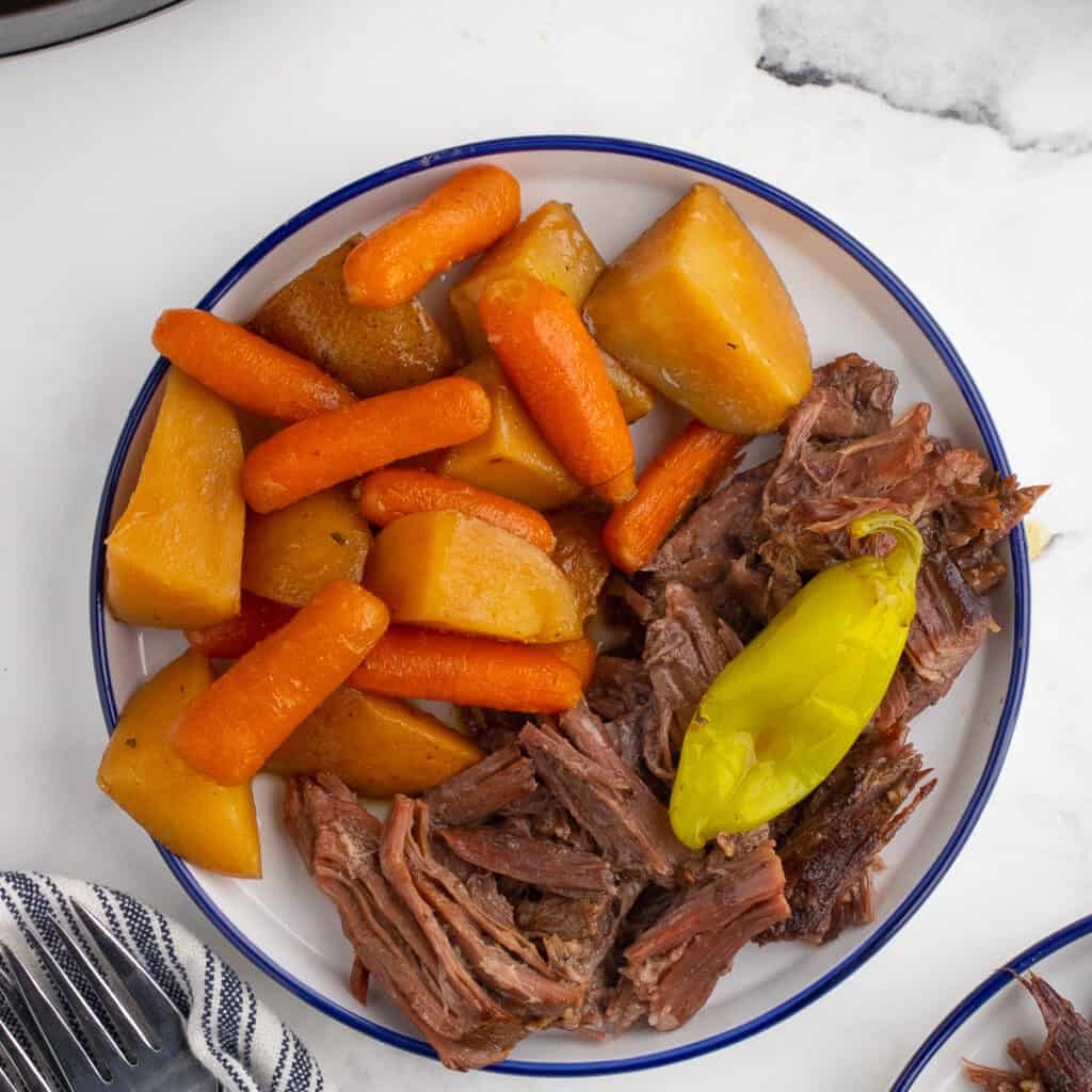 shredded pot roast with veggies on a white plate
