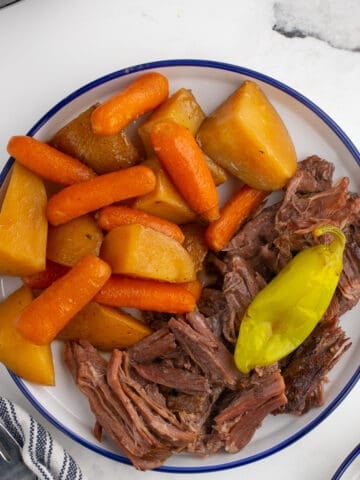 shredded pot roast with veggies on a white plate