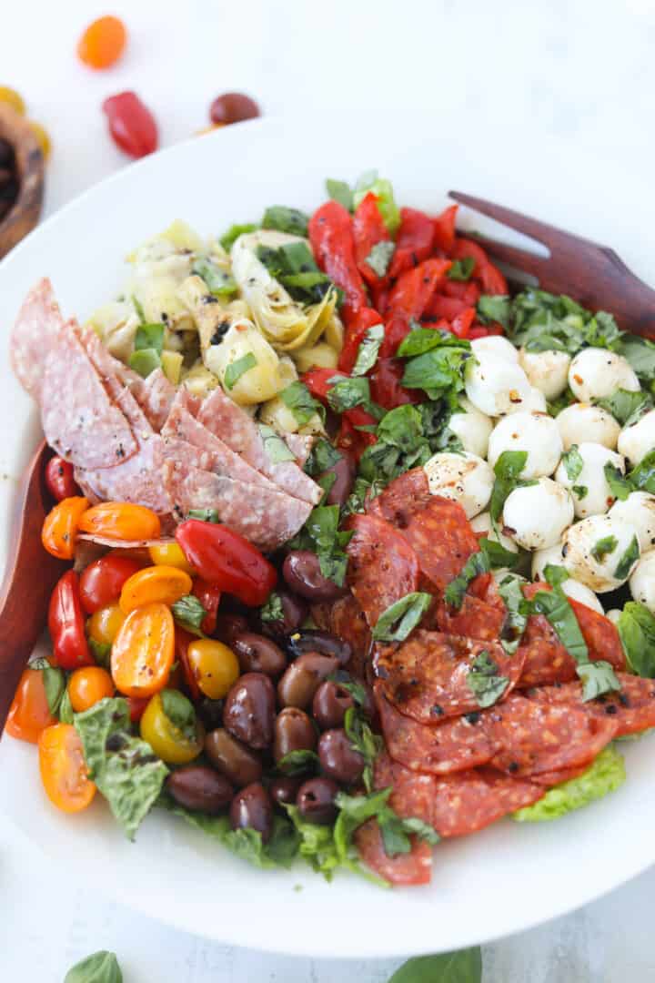 antipasto salad recipe in a serving bowl with salad tongs