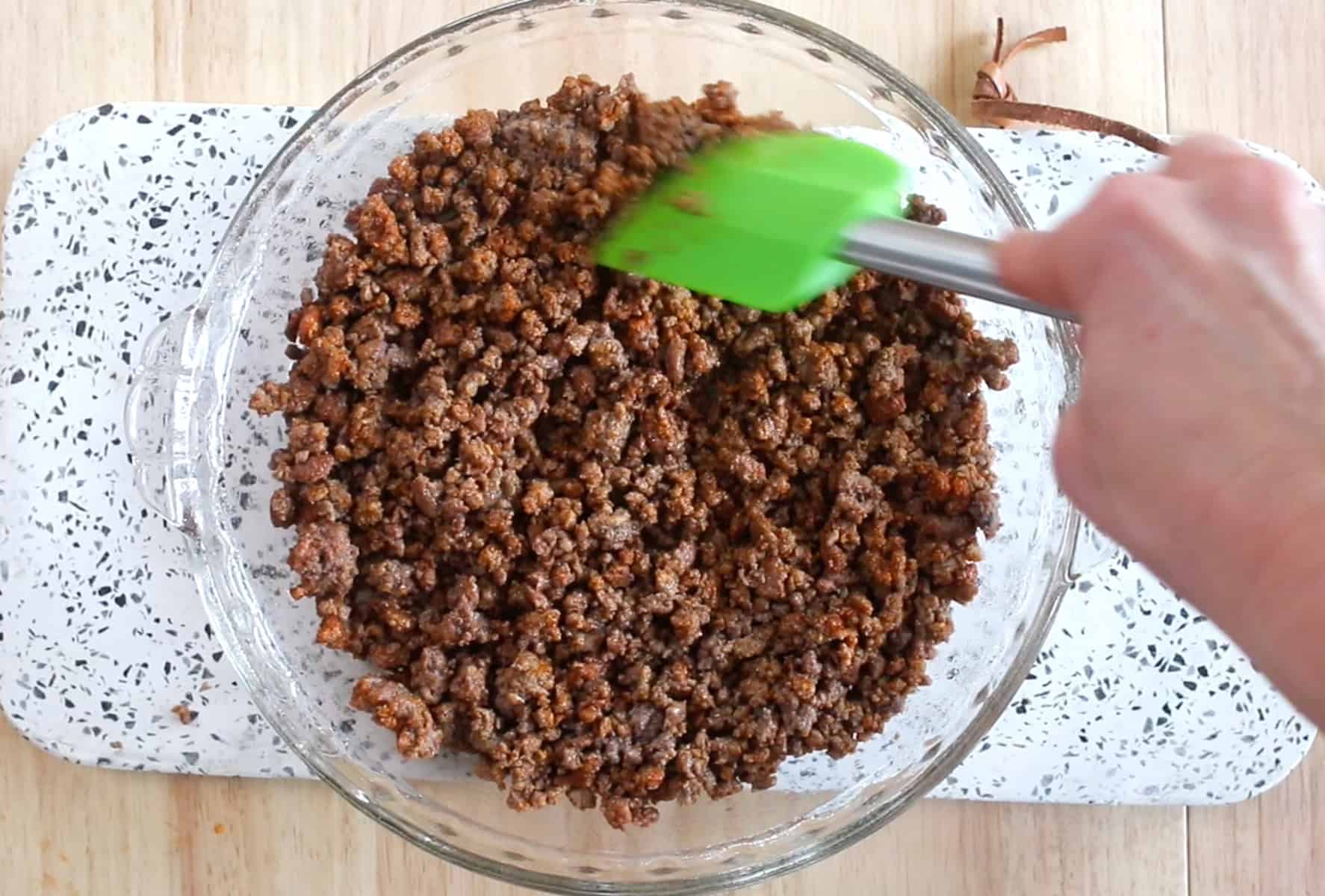 browning the ground beef and adding it to a glass pan