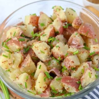 mustard potato salad in a clear bowl is a great side for pork steak