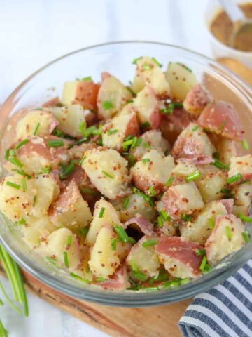 mustard potato salad in a clear bowl is a great side for pork steak